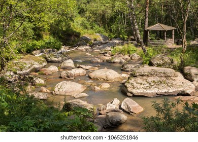 Wooden arbor on the bank of the mountain river Belokurikha on terrenkur health trail