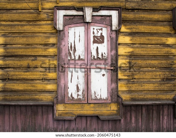 Wooden architecture of Siberia, old Windows with\
wooden carved architraves. old peeling paint on the wooden\
Windows