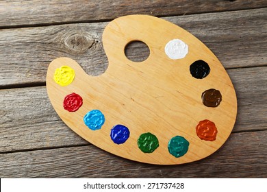 Wooden art palette with paints on grey wooden background