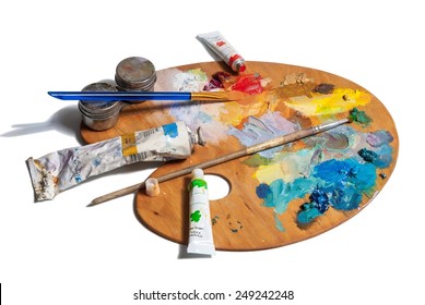 Wooden art palette with  tubes of oil paints and a brushes isolated on white background