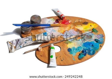 Wooden art palette with  tubes of oil paints and a brushes isolated on white background