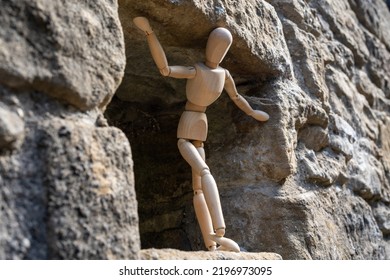 A Wooden Artist's Figure Standing, Looking Out Of A Stone Building. Concept Of An Uncertain Future, Worry And Concern.