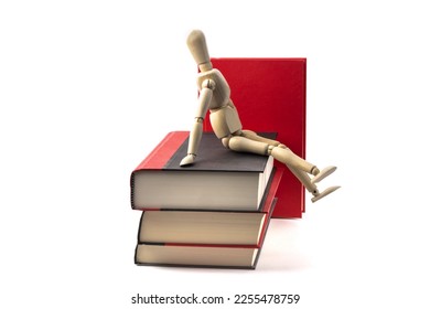A wooden artist's mannequin sitting a pile of books isolated on white - Shutterstock ID 2255478759