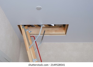 Wooden Attic Stairs Against A White Ceiling In A Private Cottage