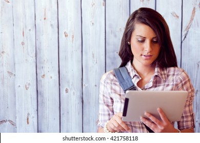Wooden background against young focused student using a tablet computer