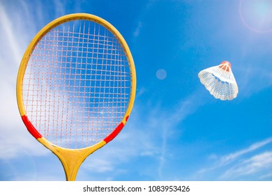 Wooden Badminton Racket And Shuttlecock Flying Against The Blue Sky And Sun Background