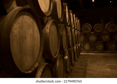 Wooden Barrels Of Aged Wine. Old Wine Cellar With Many Oak Barrels, Equipment For Wine Production. Barrels In Cellar. Rows Of Wine And Cognac Barrels In The Basement Of Winery. Process Of Aging.
