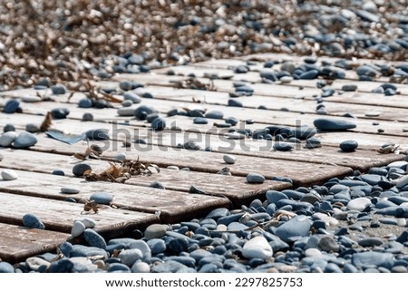 Wooden beach pathway with stones and pebbles  