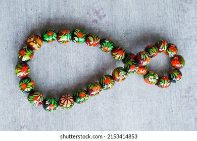 Wooden Beads In Slavic Folk Style On The Bright Wooden Table. Bead Necklace From The Carpathians. Slavic Folk Costume Necklace. Hand-painted With Flowers In The Ukrainian Style. Petrykiwka Painting.