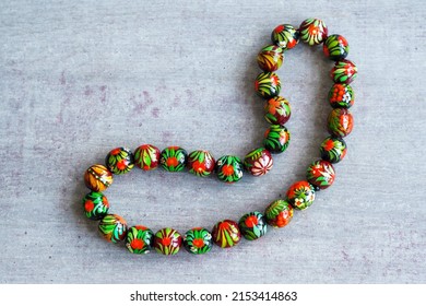 Wooden Beads In Slavic Folk Style On The Bright Wooden Table. Bead Necklace From The Carpathians. Slavic Folk Costume Necklace. Hand-painted With Flowers In The Ukrainian Style. Petrykiwka Painting.