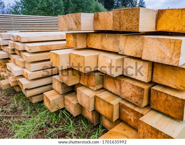 Wooden beams of different sizes. Lumber. Concept -\
sale of wood for construction. Piles of wooden beams lie on the\
ground. Concept - Buying wooden slings for building a house.\
Open-air lumber
