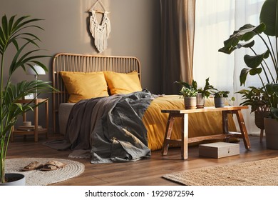 Wooden Bed In Stylish Neutral Bedroom Interior With Design Furniture, Decoration, Carpet, Bench, Tropical Plants, Bed Sheets, Blanket, Pillows And Elegant Personal Accessories In Home Decor.