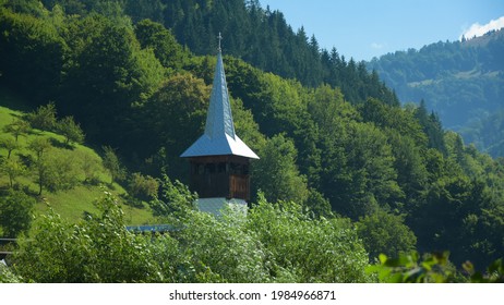 Wooden bell tower of an old orthodox church located in Maramures County. The church is located in a rural landscape, on a forested hill. Carpathia, Romania.