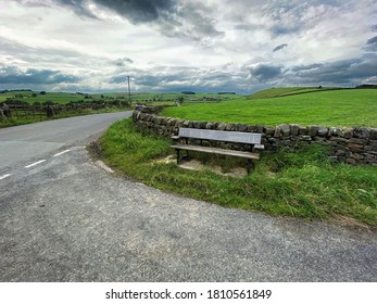 Wooden bench, high on the hills on Cringles Lane, with dry stone walls, and a cloudy sky near, Silsden, Keighley, UK