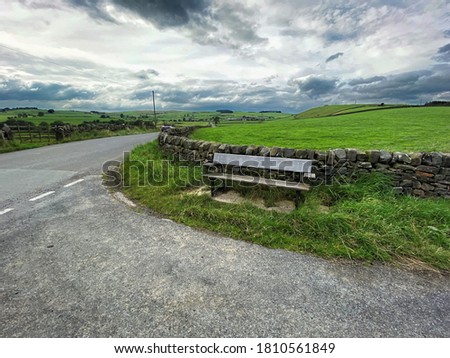 Wooden bench, high on the hills on Cringles Lane, with dry stone walls, and a cloudy sky near, Silsden, Keighley, UK