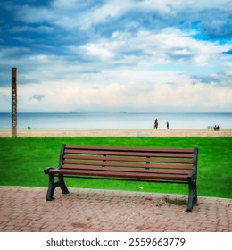 A wooden bench on a brick pathway overlooks a calm beach with a vast cloudy sky and ocean in the background. - Powered by Shutterstock