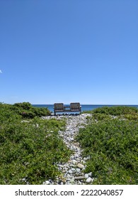 Wooden Bench On A Cobble Path Looking Out Onto The Ocean