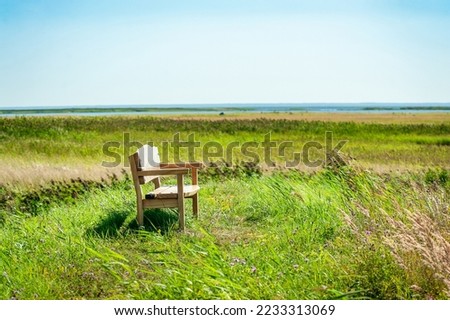 Wooden bench overlooking the Baltic Sea and seaside meadows. Beautiful sunny view of sea coast, Estonia.