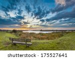 Wooden Bench overlooking a Beautiful Cloudscape above a Lake during Sunrise