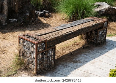A wooden bench, piece of wood, or railway sleeper with legs made from stones.