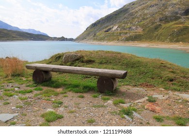 Wooden Bench, Bench At The Reservoir Monte Spluga, At The Splügen Pass, And Surrounding Mountains In Summer 