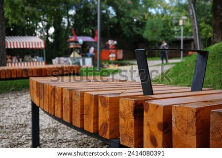 Wooden bench in the seating area of the children's playground and popcorn, cotton candy and toy street vendor stands in the Artificial Lake park, Tirane, Albania