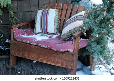 Wooden Bench With Snow Dusted Pink Cushions On A Front Porch