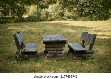 Wooden bench and table near the lake in city park. Concept of outdoor family picnic near a town.