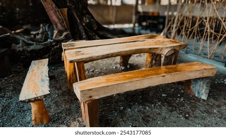 A wooden bench and a wooden table are sitting in a dirt field. The bench is empty and the table is covered in water - Powered by Shutterstock