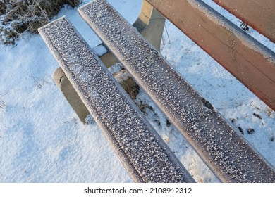 Wooden bench in a winter park covered with hoarfrost