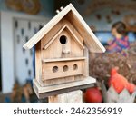 A wooden bird feeder near house. Selective focus on the part of the feeder