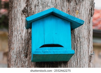 Wooden birdhouse painted in vibrant blue provides shelter for birds in a natural setting - Powered by Shutterstock