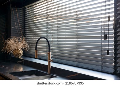Wooden blinds black color closeup on the window. Bamboo slats 50mm wide. Venetian wood blinds in the kitchen. Black tapes. Sink with copper faucet near the window. Round vase is on the windowsill. - Shutterstock ID 2186787335