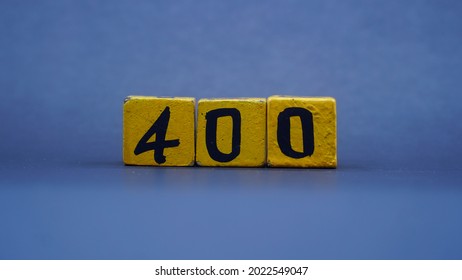 Wooden block with number 400. Yellow color on dark background. Focus selected