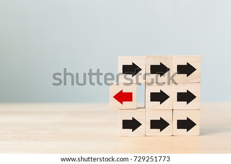Wooden block with red arrow facing the opposite direction black arrows, Unique, think different, individual and standing out from the crowd concept
