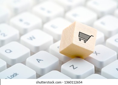Wooden block with shopping cart graphic on computer keyboard. Online shopping concept. 