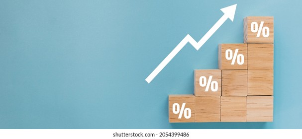 Wooden block signs and symbols with percentage sign and up arrow financial and business growth interest rates and mortgage rates interest on investment inflation concept on blue background.