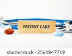 A wooden block that says patient care sits among medical tools and medications, emphasizing the vital link between healthcare and technology for better patient outcomes.