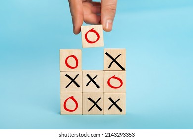 Wooden block tic tac toe board game. Business marketing strategy planning concept. Hand putting wooden cube block which print screen O to O and X game or tic-tac-toe elements
