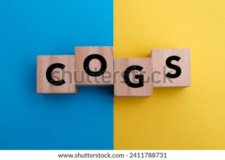 A wooden block with word “COGS” on it. COGS stands for “cost of goods sold”
