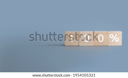 Wooden block written with 100 percent symbol on a gray background with copy space.