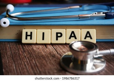 Wooden block written with HIPAA inscription with stethoscope, magnify glasses and flower.