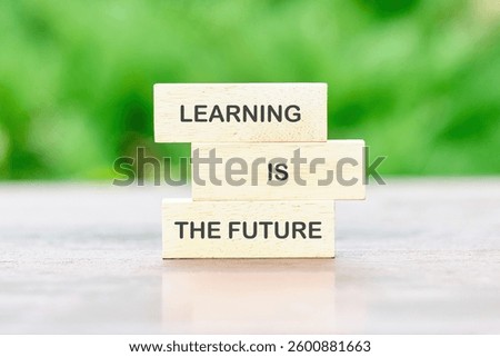 Wooden blocks are arranged to display the message learning is the future, emphasizing the importance of education in today's world against a blurred green backdrop.