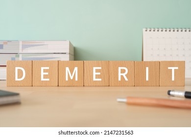 Wooden blocks with "DEMERIT" text of concept, pens, notebooks, and books. - Shutterstock ID 2147231563
