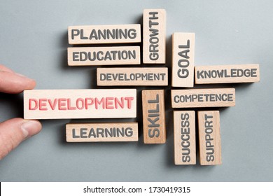 Wooden Blocks With Development, Skill, Education, Learning And Planning Concept Related Words Being Held By A Human Hand.