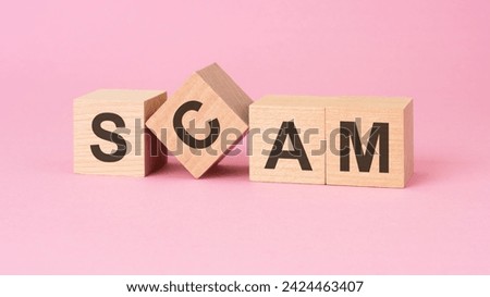 wooden blocks displaying SCAM arranged on a pink surface, suggesting deceit or fraudulent activity.