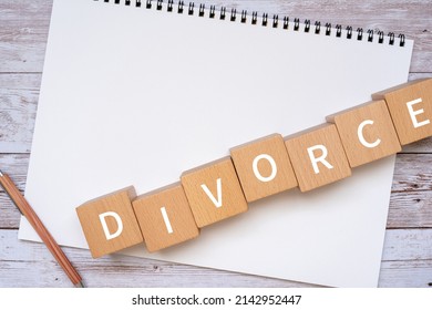 Wooden blocks with "DIVORCE" text of concept, a pen, and a notebook.
