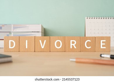 Wooden blocks with "DIVORCE" text of concept, pens, notebooks, and books.
