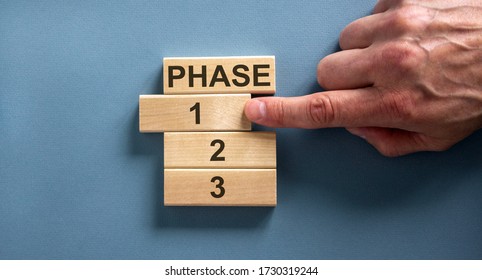 Wooden blocks form the words 'phase, 1, 2, 3,' on blue background. Male hand. Beautiful background.