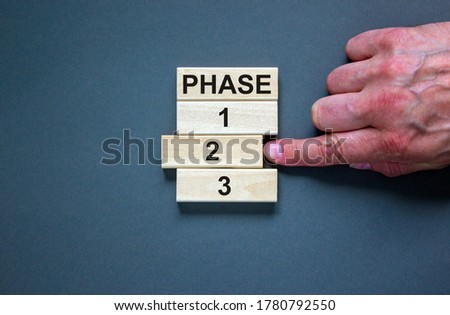 Wooden blocks form the words 'phase, 1, 2, 3,' on blue background. Male hand. Beautiful background. Business concept, copy space.